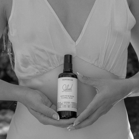 Woman holding Salud Jasmine and Rose Floral Mist to hydrate skin.